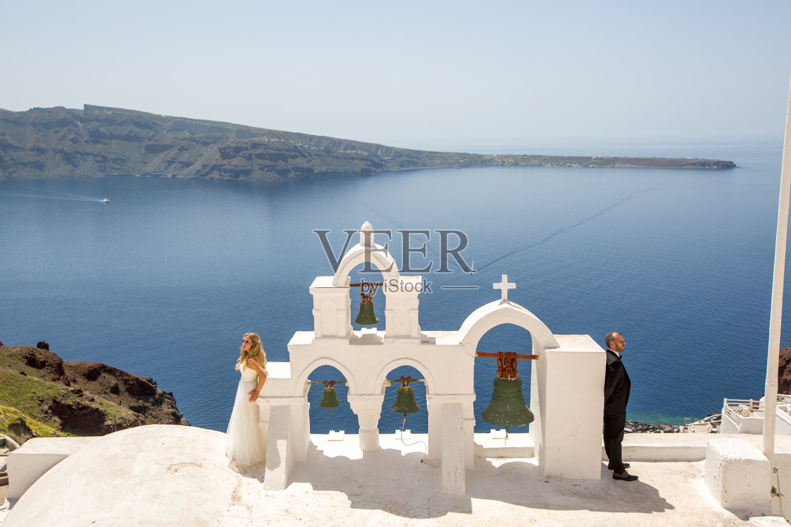 新婚夫妇走上圣托里尼岛街道的楼梯。照片摄影图片