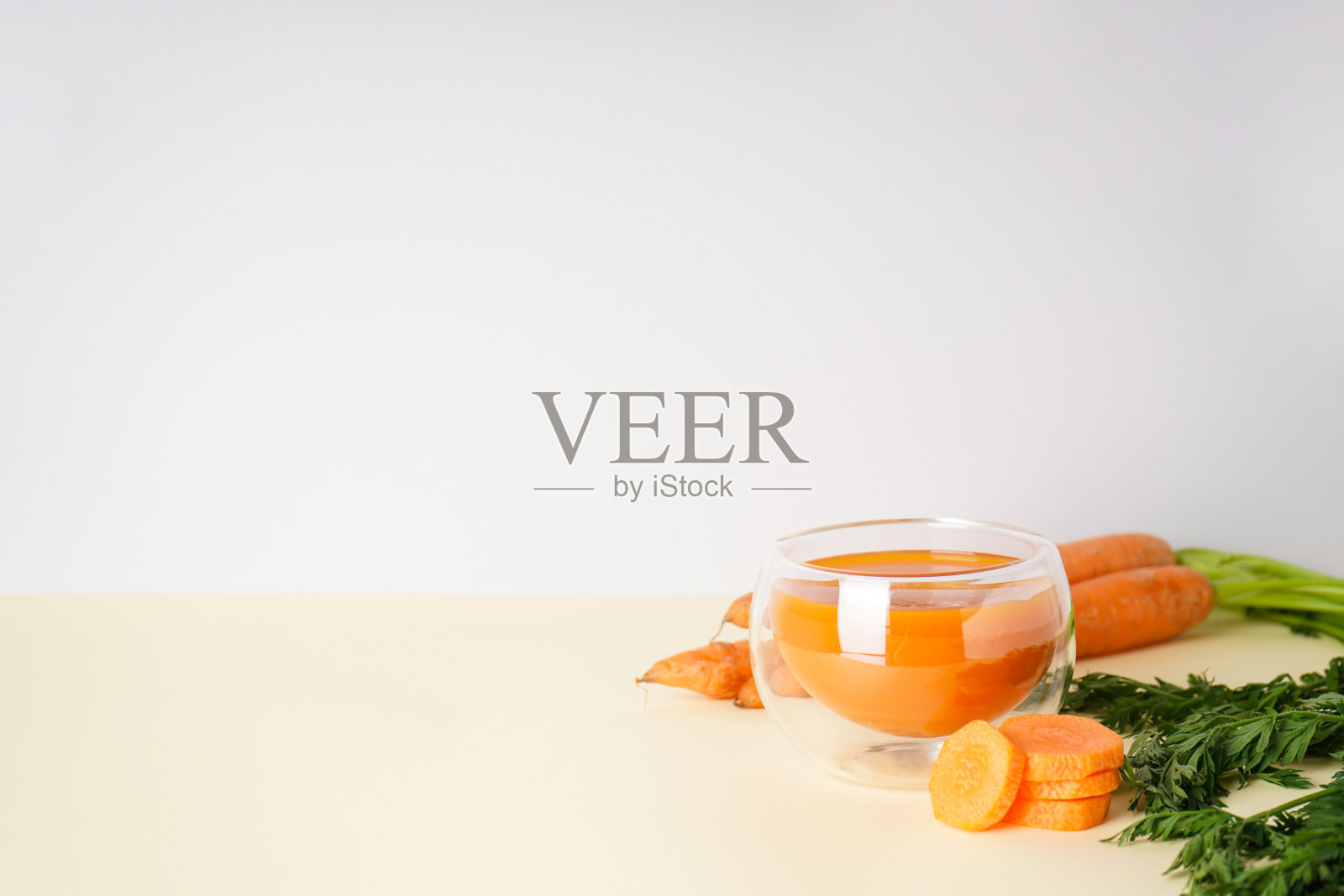 新鲜的胡萝卜汁和成熟的胡萝卜在黄色的背景，有文字空间。照片摄影图片