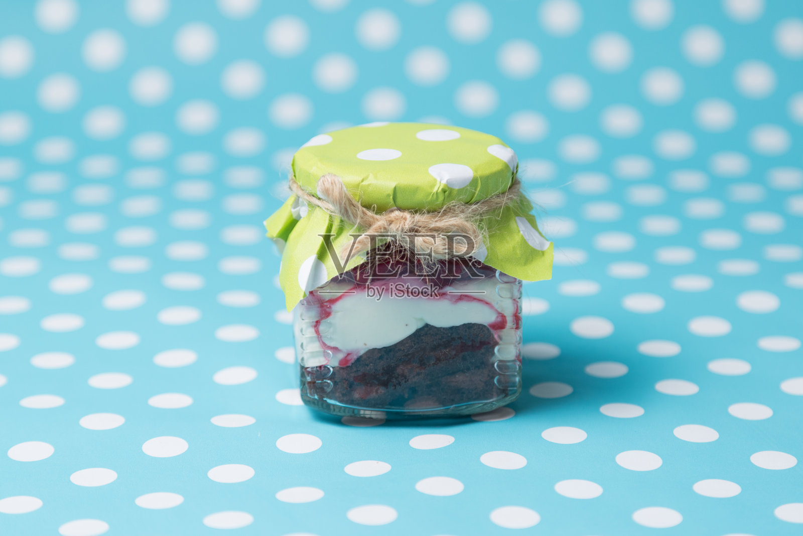 美味的蛋糕在一个罐子在蓝色背景和圆点。覆盆子和巧克力饼干照片摄影图片