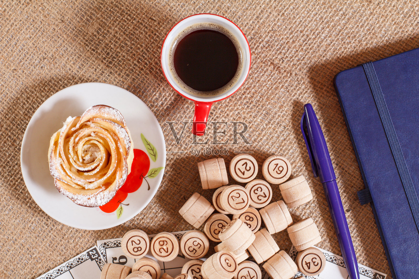 布袋上的棋盘游戏乐透。木制乐透桶袋和游戏卡笔记本，钢笔，咖啡杯和自制饼干。照片摄影图片