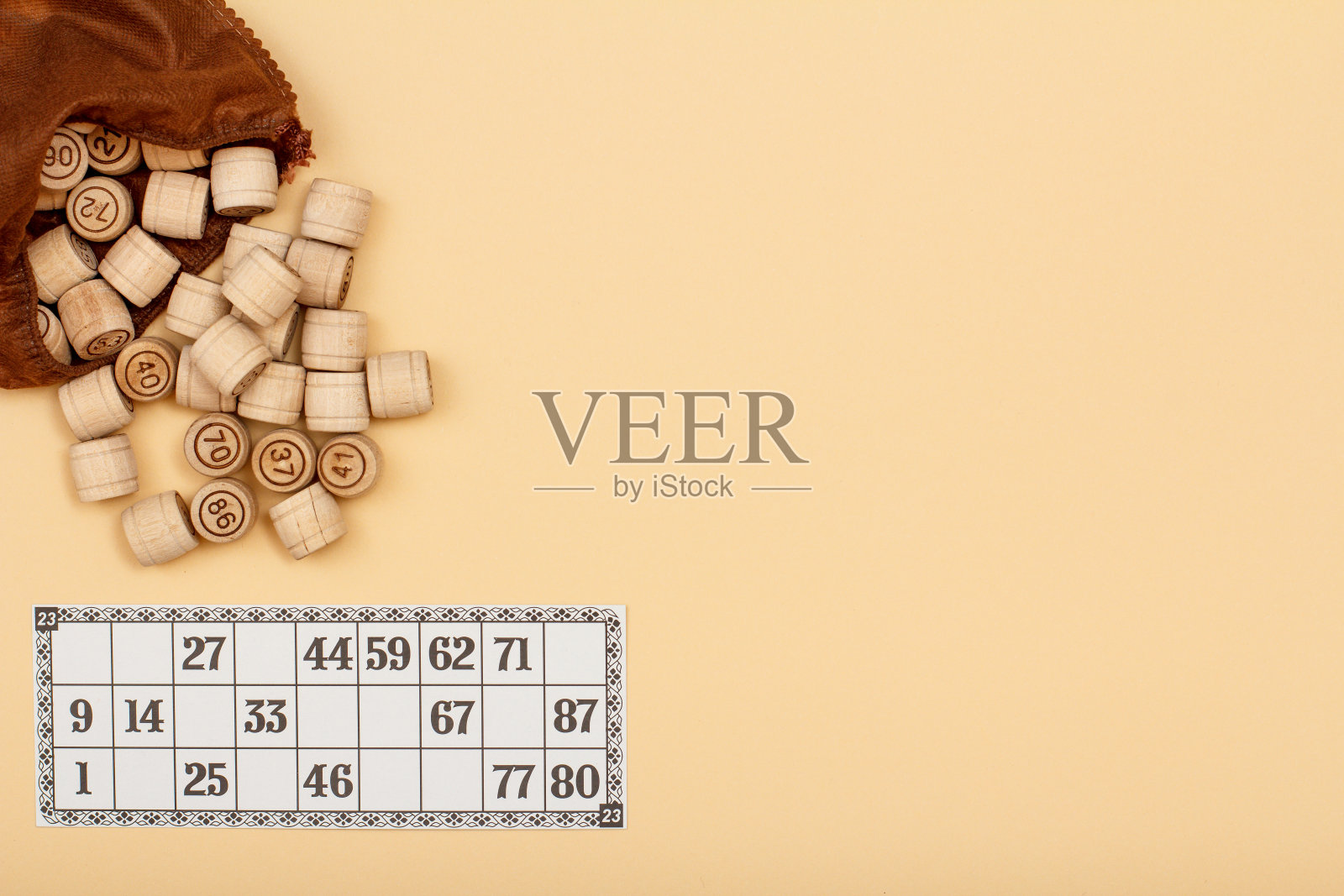 木制乐透桶与棕色的袋子和游戏卡在米色的背景照片摄影图片