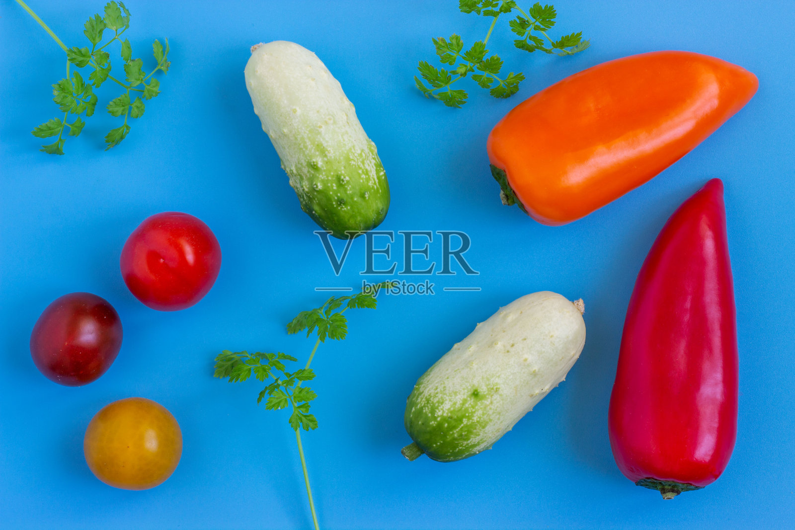 将新鲜蔬菜、黄瓜、番茄、辣椒放在蓝色背景上。健康食品的概念。平躺，俯视图。照片摄影图片