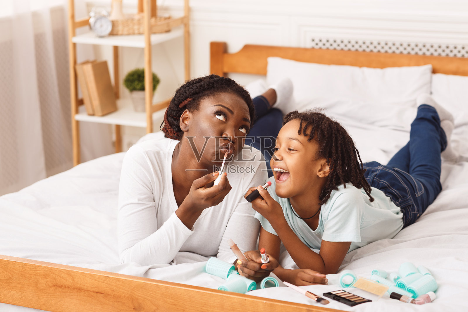 那个非洲小女孩和她妈妈在床上化妆照片摄影图片