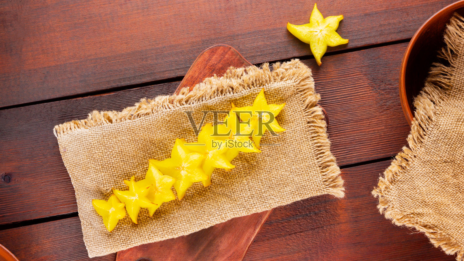 木板上的杨桃。杨桃(杨桃L.)在粗麻布上。麻衣上的黄色水果杨桃照片摄影图片