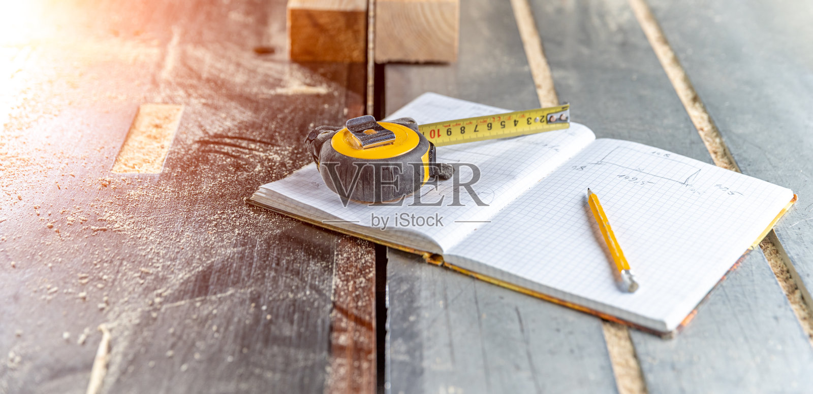 在细木工的工作簿上画出准备好的木制品。卷尺，铅笔和笔记本放在桌子上，上面有电锯照片摄影图片