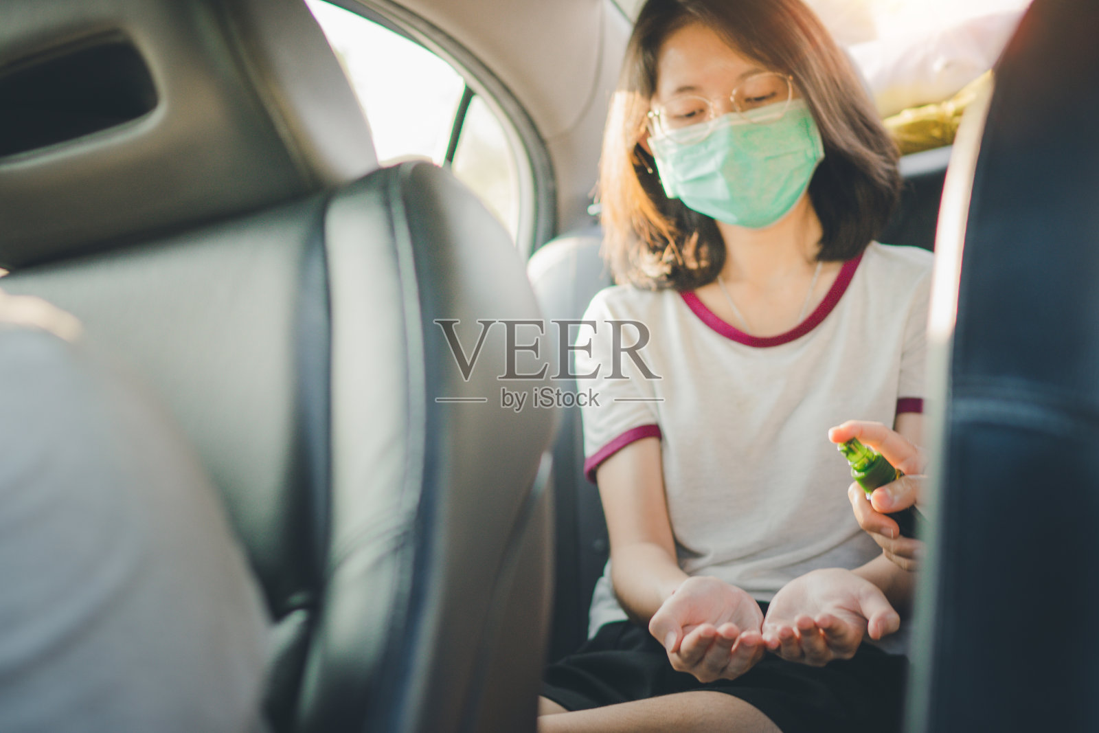 亚洲人戴口罩，手喷酒精消毒剂，防止新冠病毒传播照片摄影图片