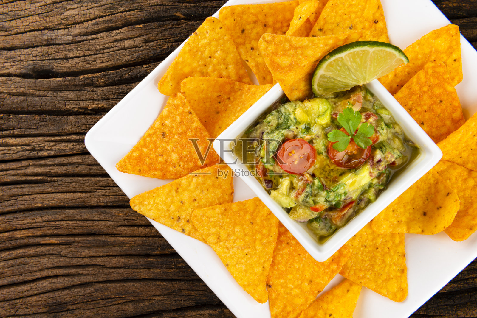 旧木桌上的鳄梨色拉酱和玉米片。烹饪素食的概念照片摄影图片