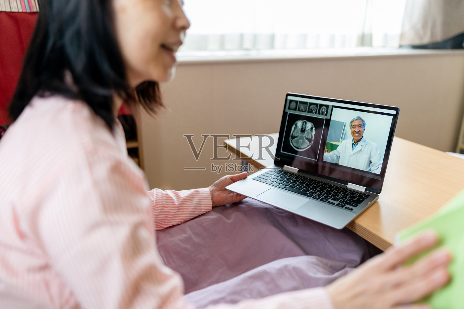 远程保健和访问护理-妇女在家里的笔记本电脑上与医生视频聊天照片摄影图片