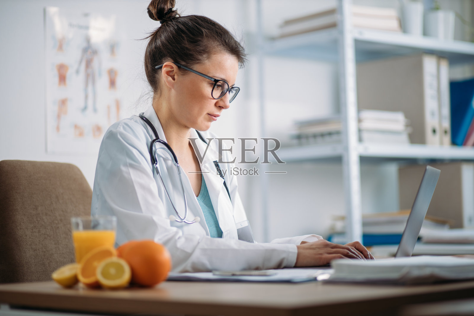 在办公室工作的女医生。年轻营养学家为肥胖病人提供减肥食谱。照片摄影图片