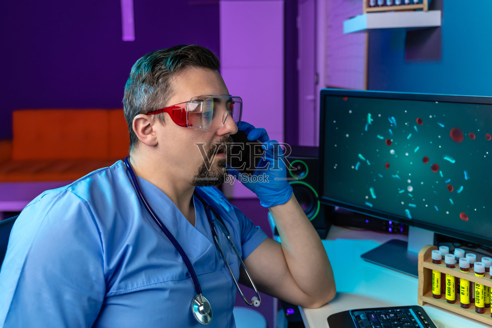 年轻医生戴着防护眼镜，正在用手机打电话照片摄影图片