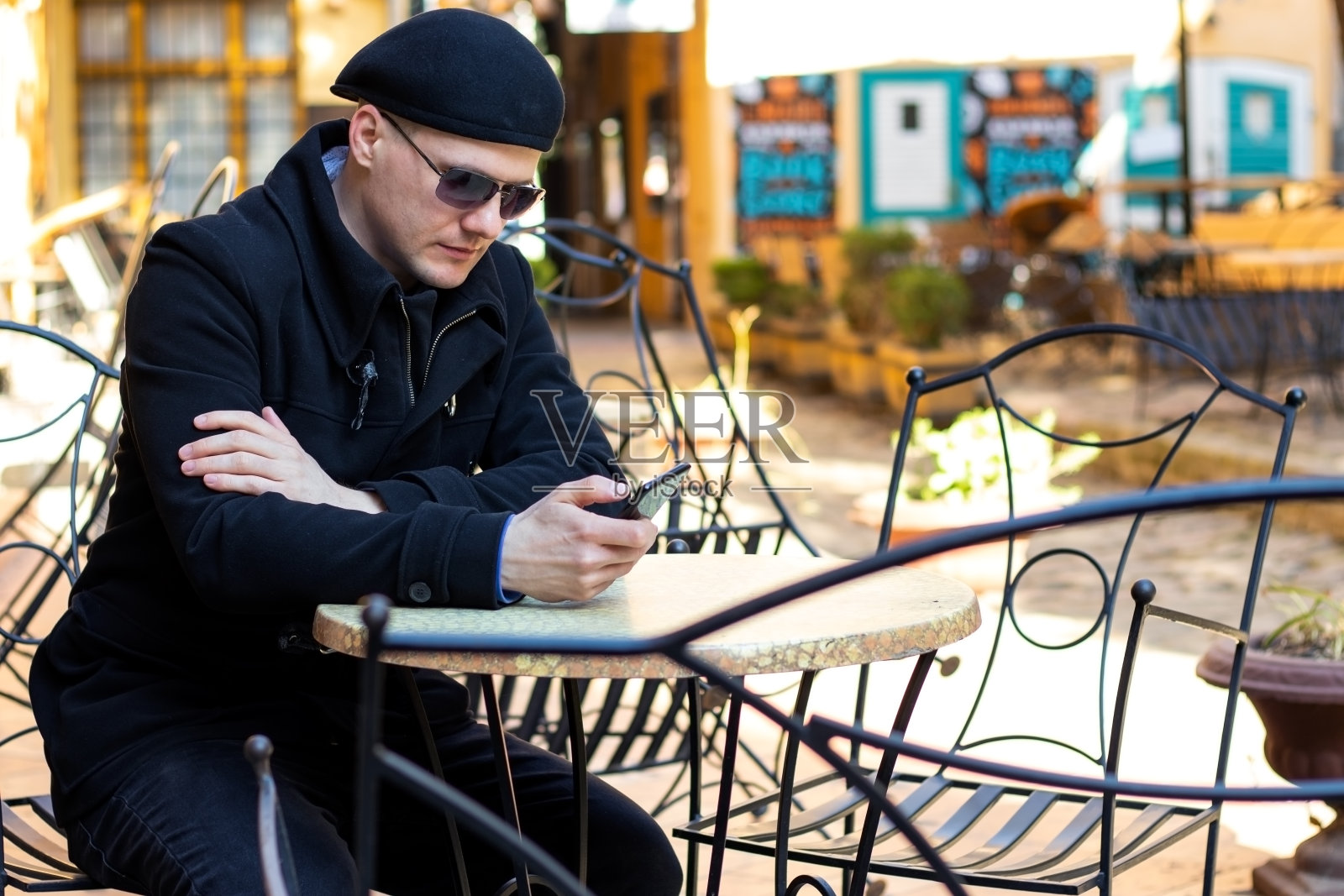 一个年轻人独自坐在外面咖啡馆露台的椅子上。照片摄影图片