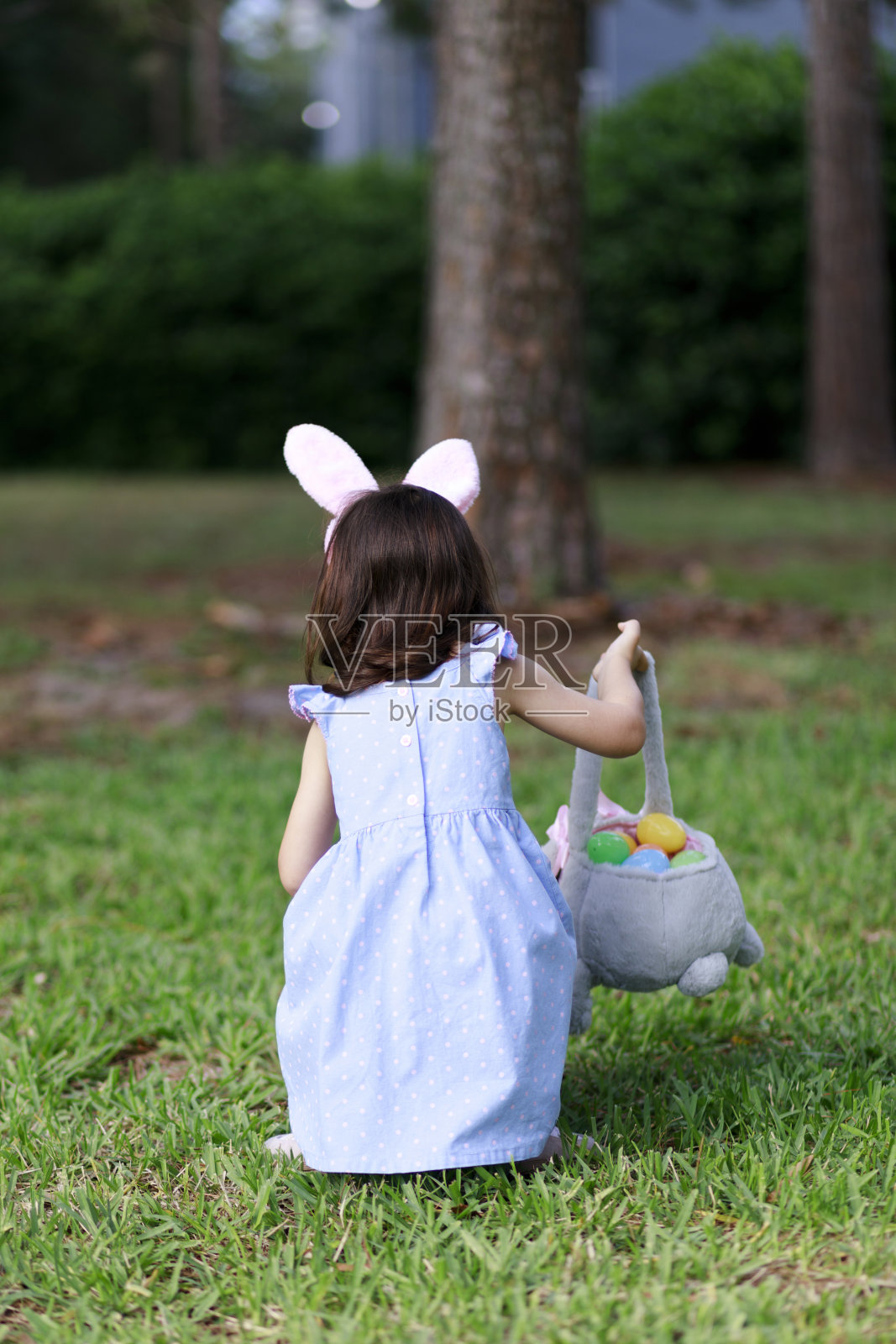 有兔耳朵的小女孩。寻找复活节彩蛋照片摄影图片