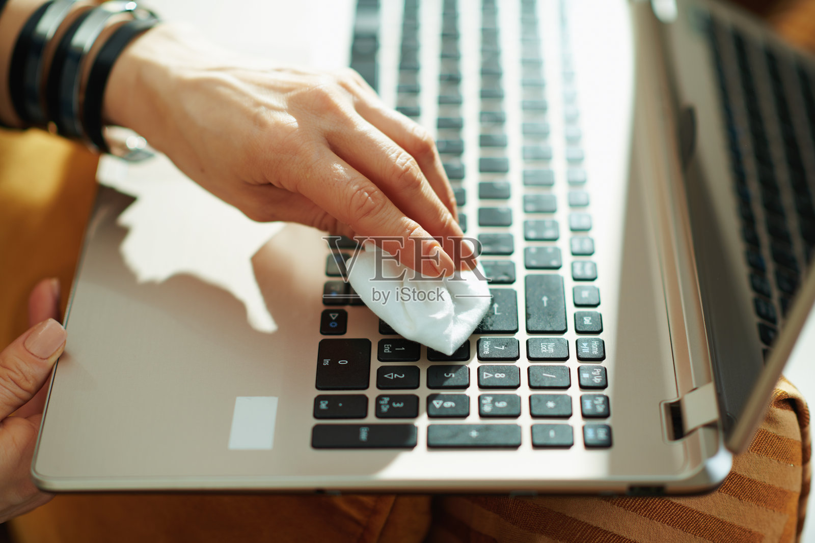 女人用清洁布擦拭笔记本电脑的特写照片摄影图片