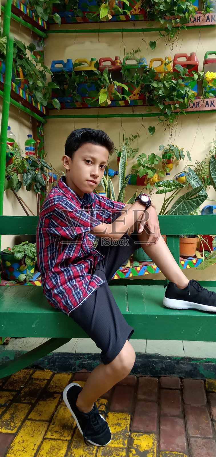 印尼吉他手正在他的时间放松附近的一个商店旁边的花园景观。照片摄影图片