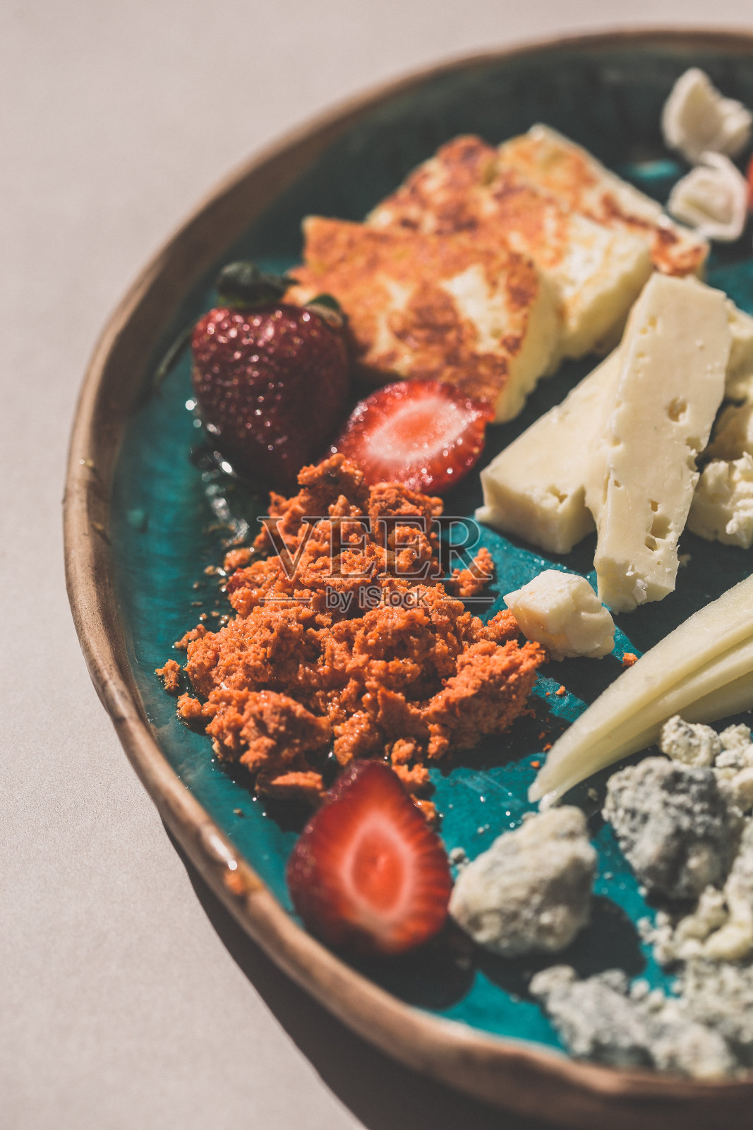 用陶瓷盘子盛着各种各样的奶酪的地中海奶酪拼盘。照片摄影图片