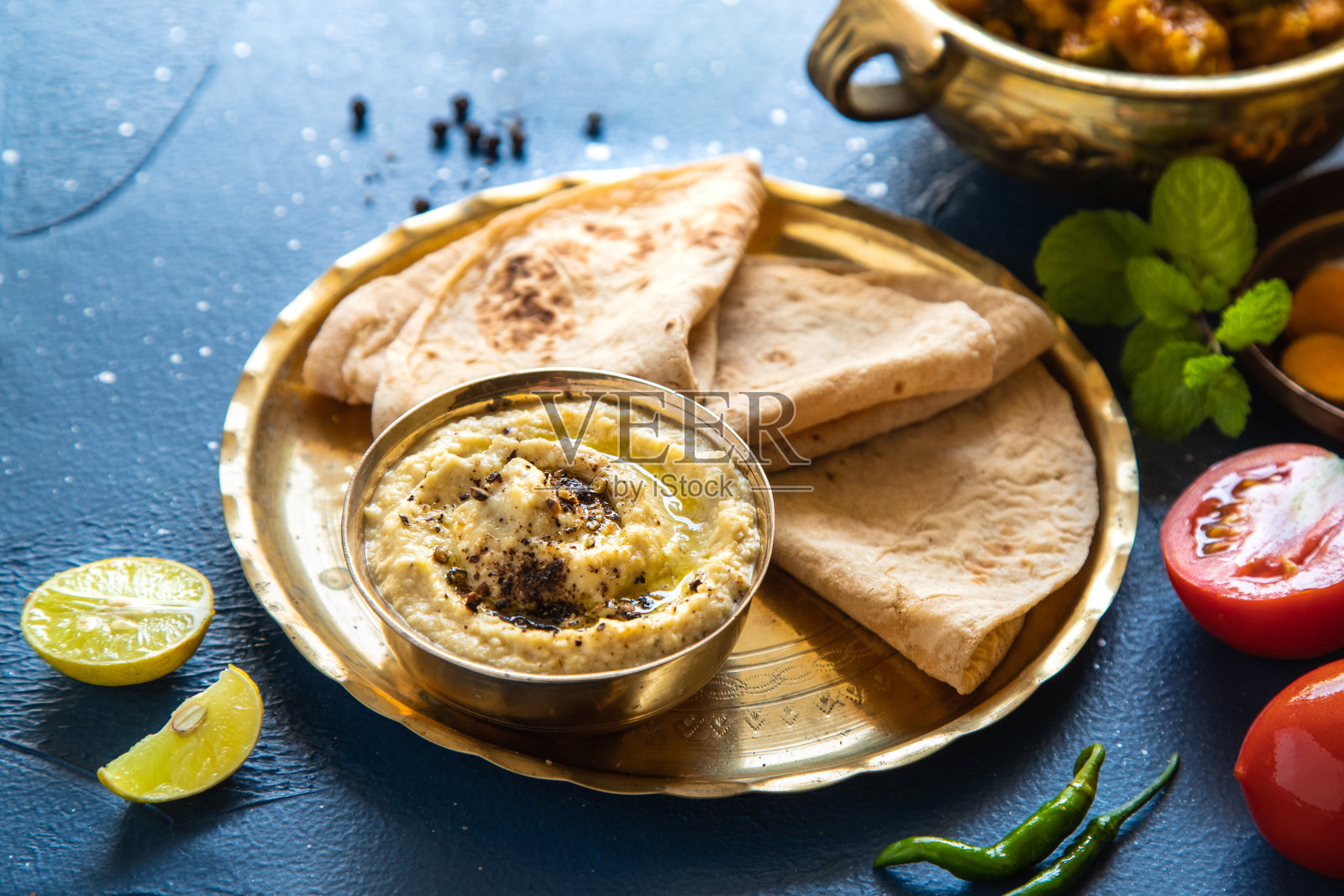 东方食物——印度奶酪配薄饼和酱汁。印度菜。印度咖喱铜黄铜配料在蓝色背景特写，印度食物。照片摄影图片
