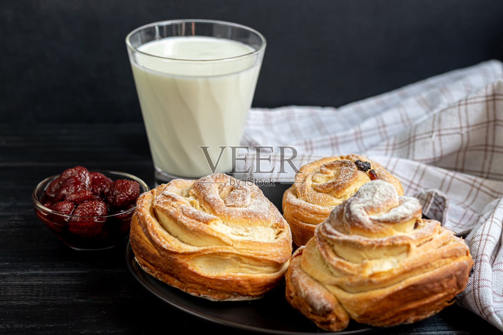 带有葡萄干和干果的烘焙产品位于深色木质背景上。撒上糖粉。Kraffins。复活节食物。照片摄影图片