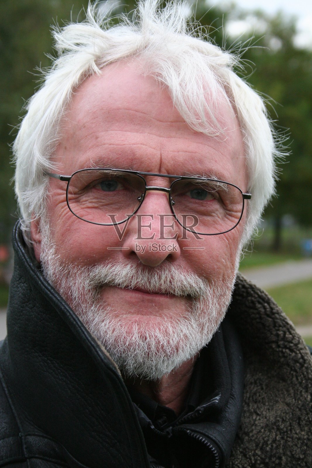 近距离肖像的白胡子高级眼镜和长长的黑色皮衣站在外面的公园照片摄影图片