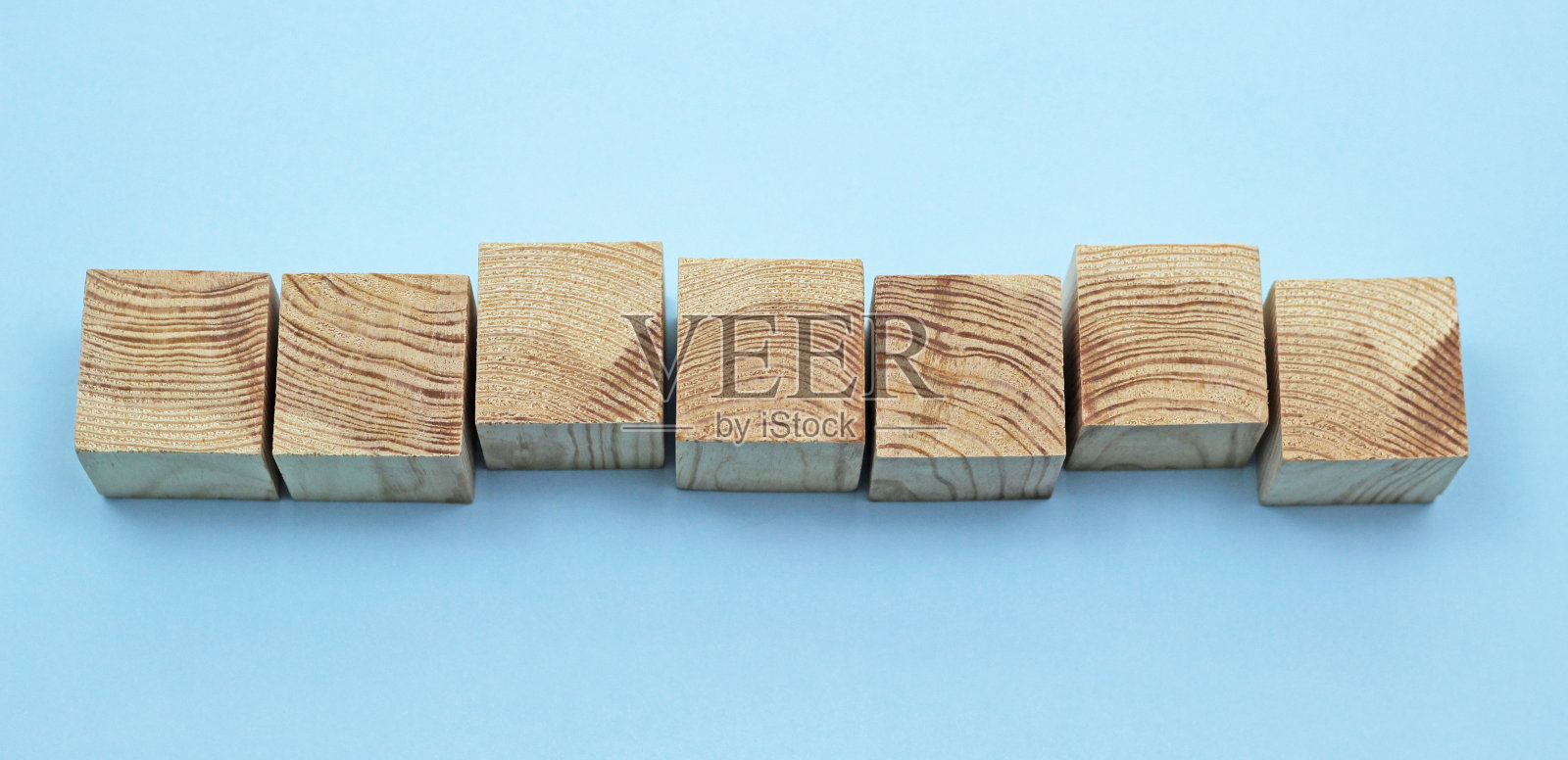 七个木制立方体玩具排成一行，以蓝色为背景照片摄影图片