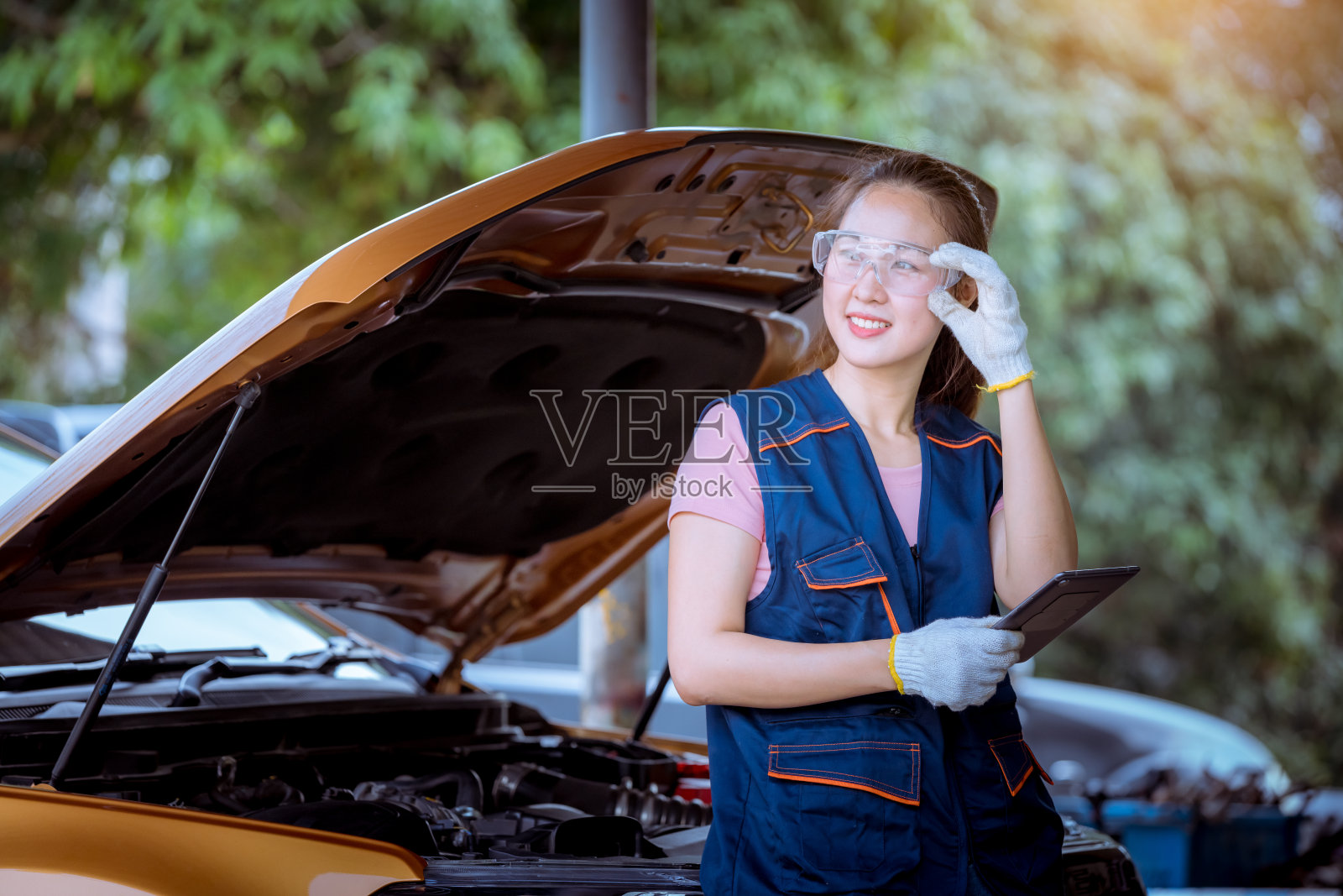 一名女性汽车机修工在汽车修理厂修理汽车，并检查发动机油的水平，以补充或清洁照片摄影图片