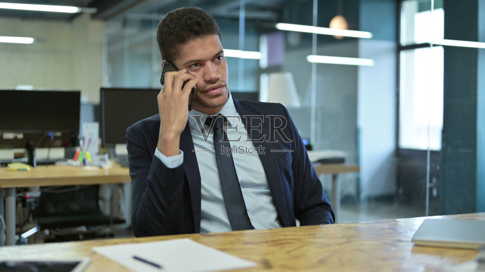 年轻的非洲商人在办公室里用智能手机聊天照片摄影图片