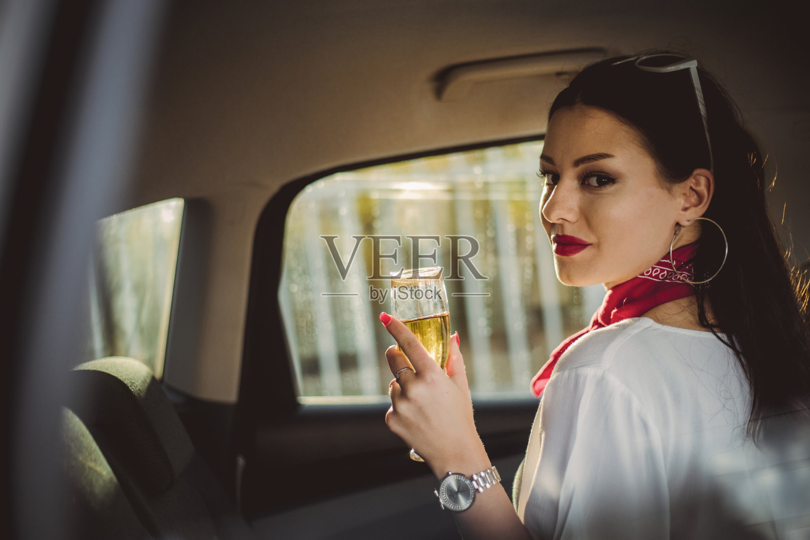 女商人开车旅行，坐在后座喝香槟照片摄影图片