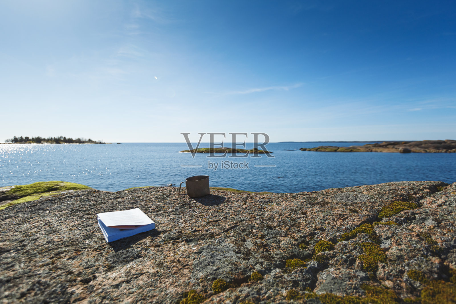 在海边的石头上放着一本书。照片摄影图片