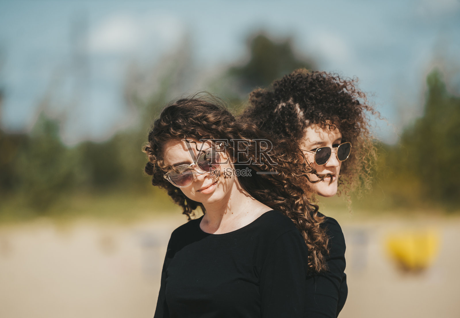 时尚风格的肖像年轻漂亮时髦的女孩长卷发戴着黑色太阳镜照片摄影图片