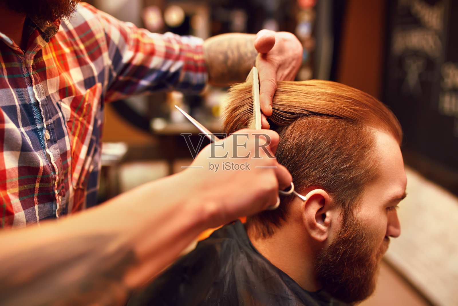 一个留着胡子的年轻人到理发师那里理发。照片摄影图片