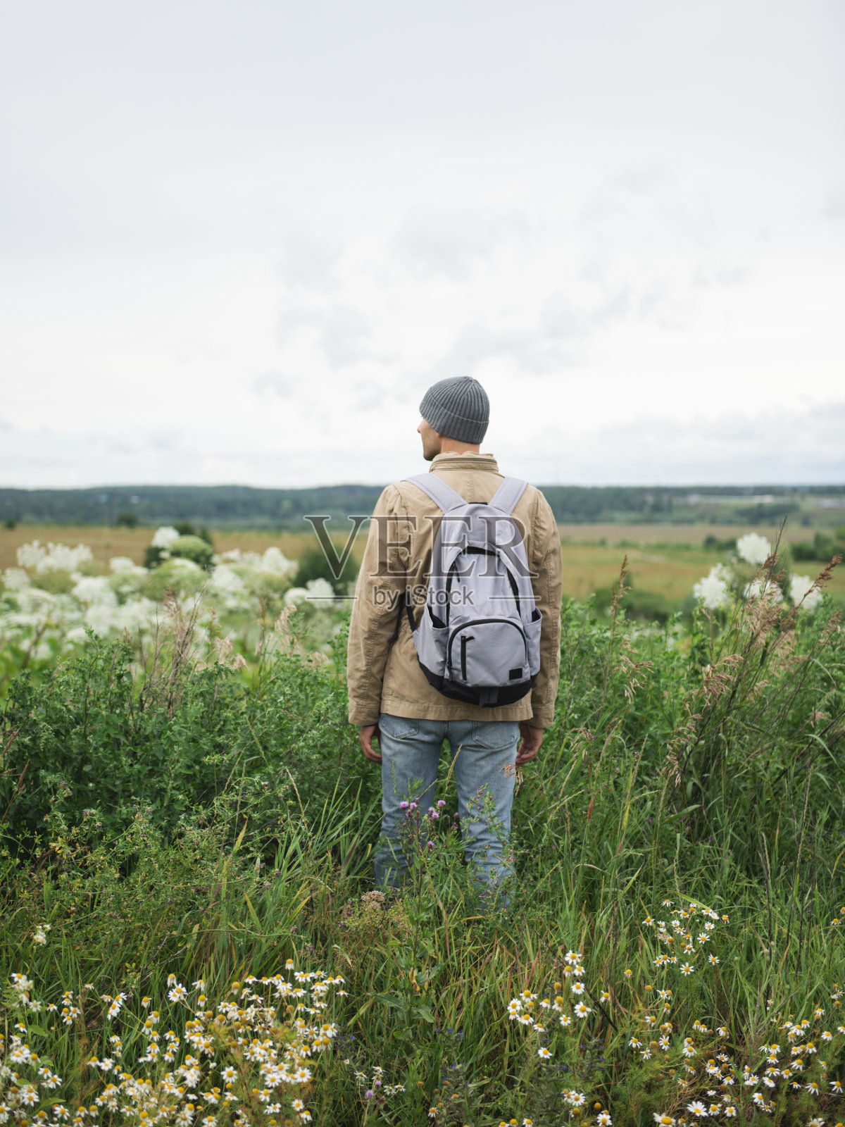 背包男徒步者站在农村地区的田野里照片摄影图片