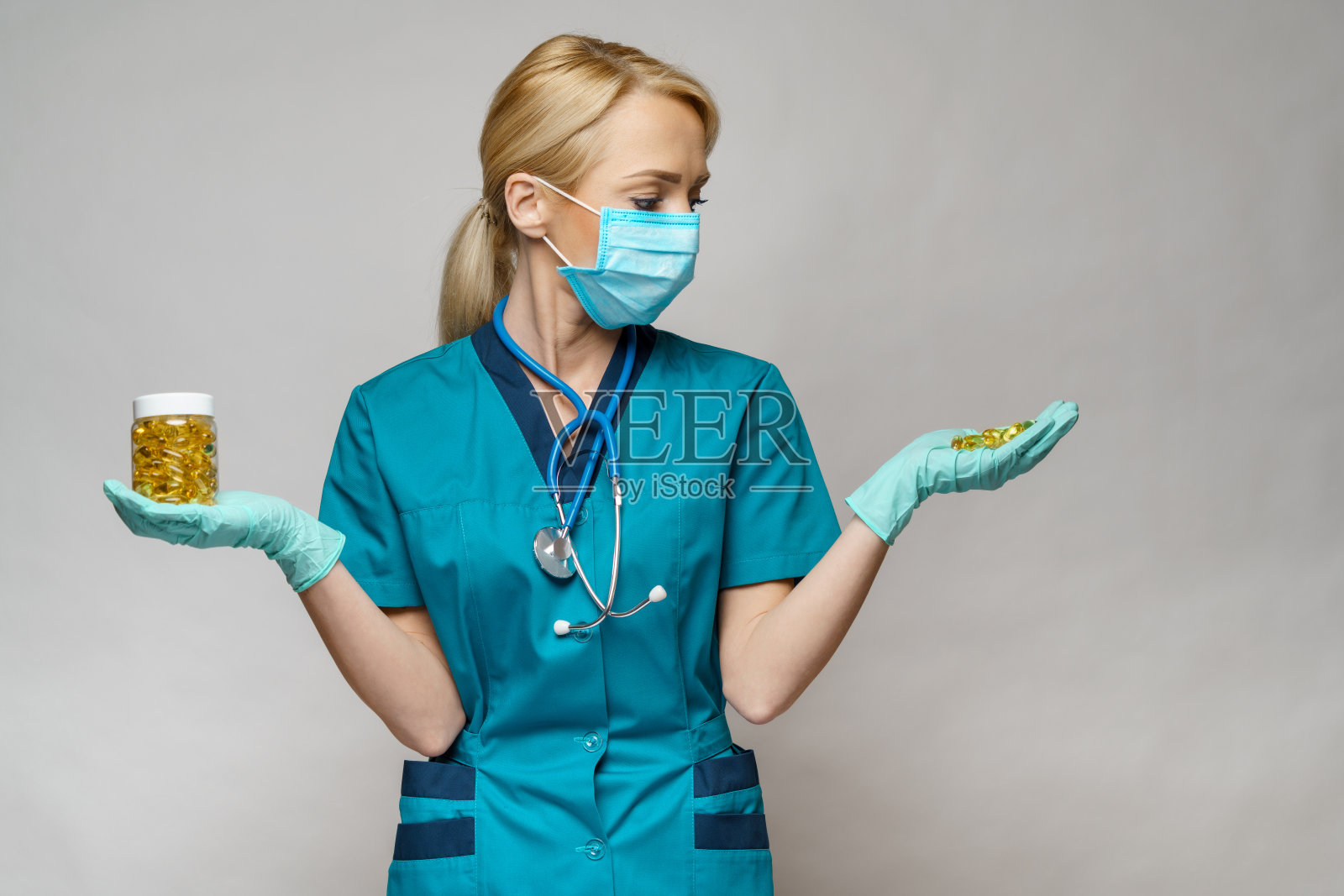 戴着防护口罩和橡胶或乳胶手套的女医生护士 - 拿着一罐药丸照片摄影图片