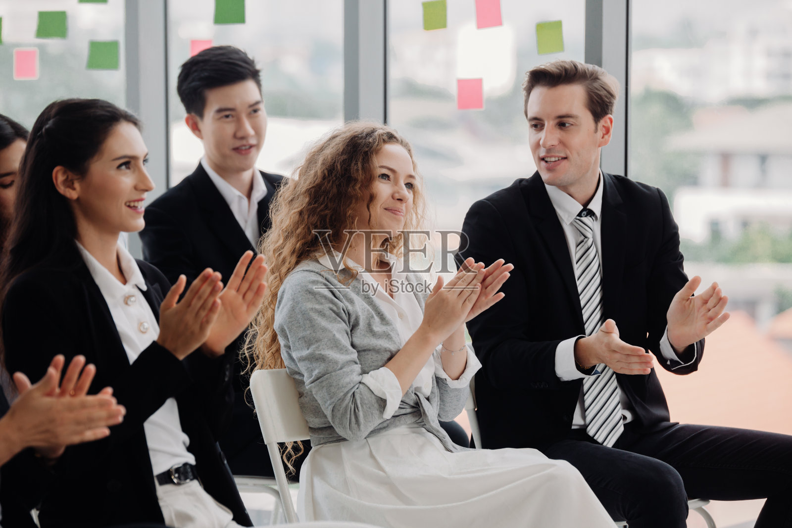 一群穿着正装的快乐商务人士坐在会议厅的椅子上鼓掌照片摄影图片