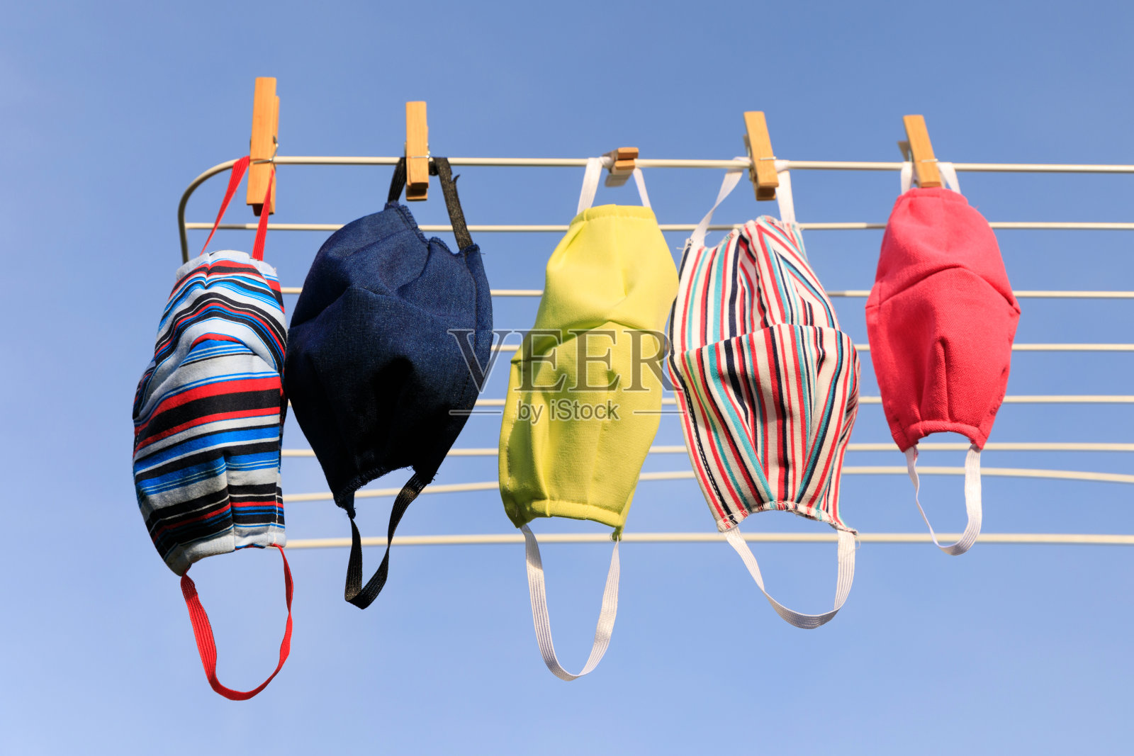 在Covid-19病毒爆发期间，为了清洁和卫生，清洗后挂在户外衣架上的卫生口罩。晾晒后的口罩挂在阳光下使用消毒。照片摄影图片