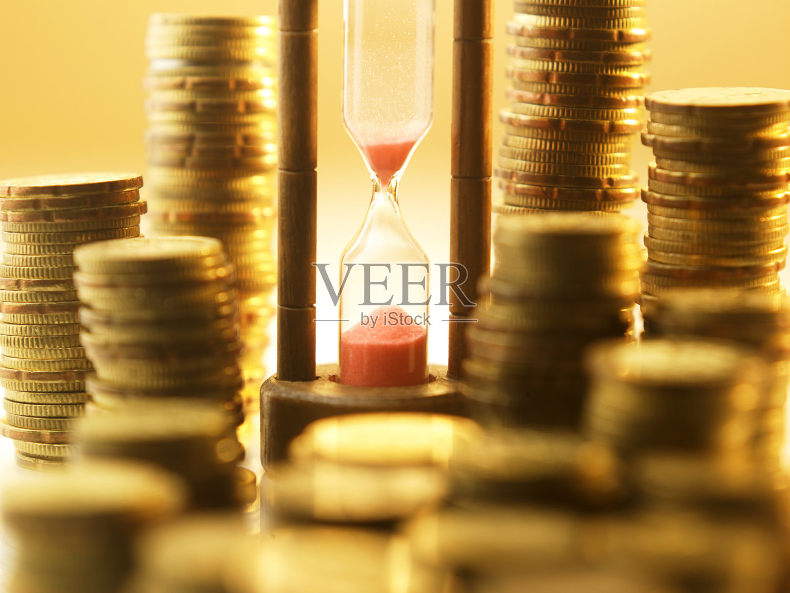 沙漏上多堆硬币照片摄影图片