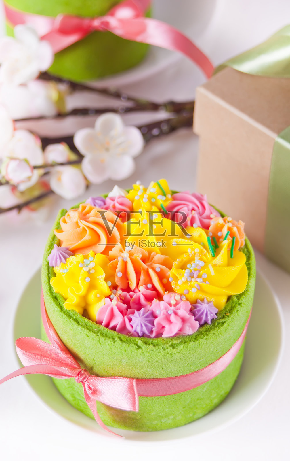 春节复活节餐桌。小的绿色蛋糕，背景上有奶油花和五颜六色的鸡蛋。照片摄影图片