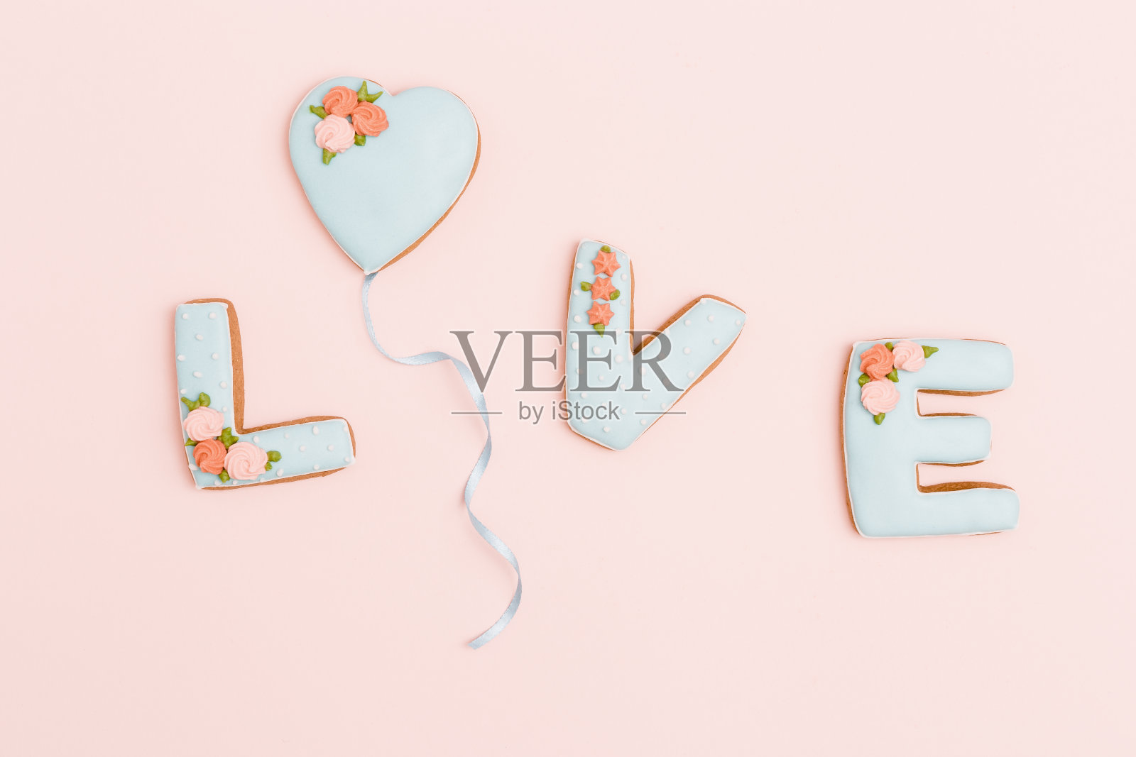 心形姜饼，爱的字母形状的饼干，以粉霜为背景。情人节作文或问候明信片与文本的复制空间。最小的风格。照片摄影图片