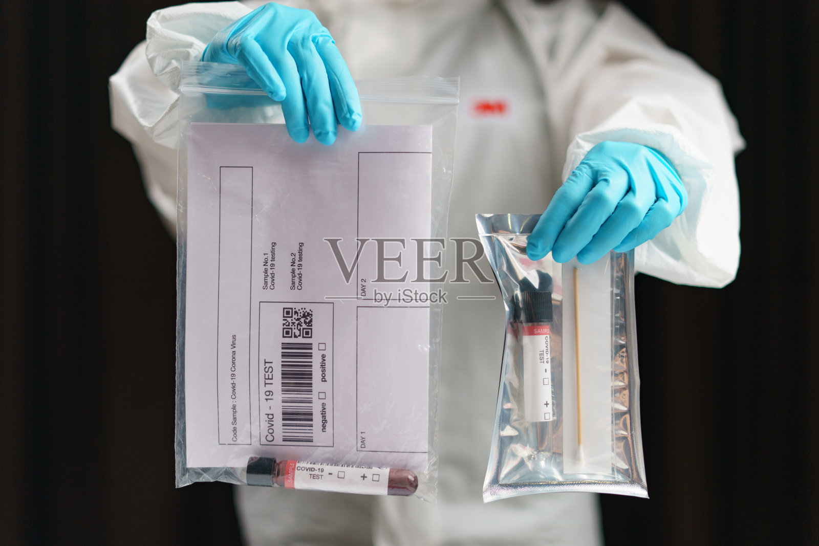 冠状病毒检测过程中，一手拿管血液检测样本和拭子采集试剂盒采集样本进行样品检测。(假的QR码/条形码)照片摄影图片