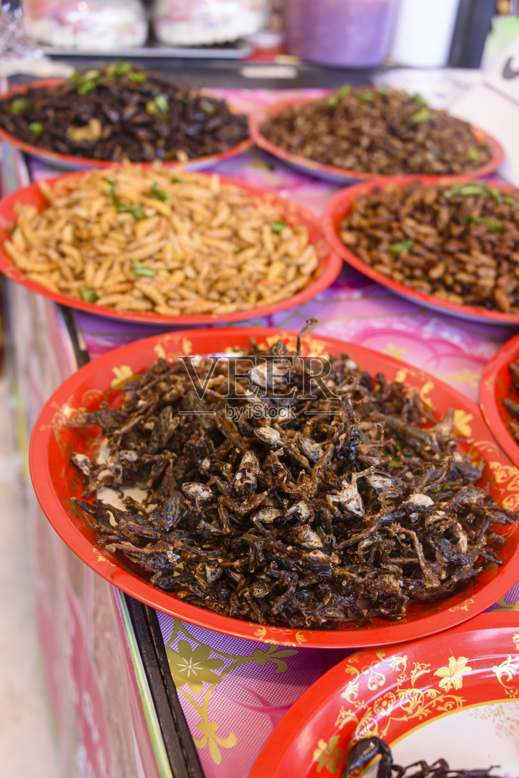 在泰国普吉岛的一个街头食品市场上，一碗一碗的油炸昆虫幼虫在出售照片摄影图片