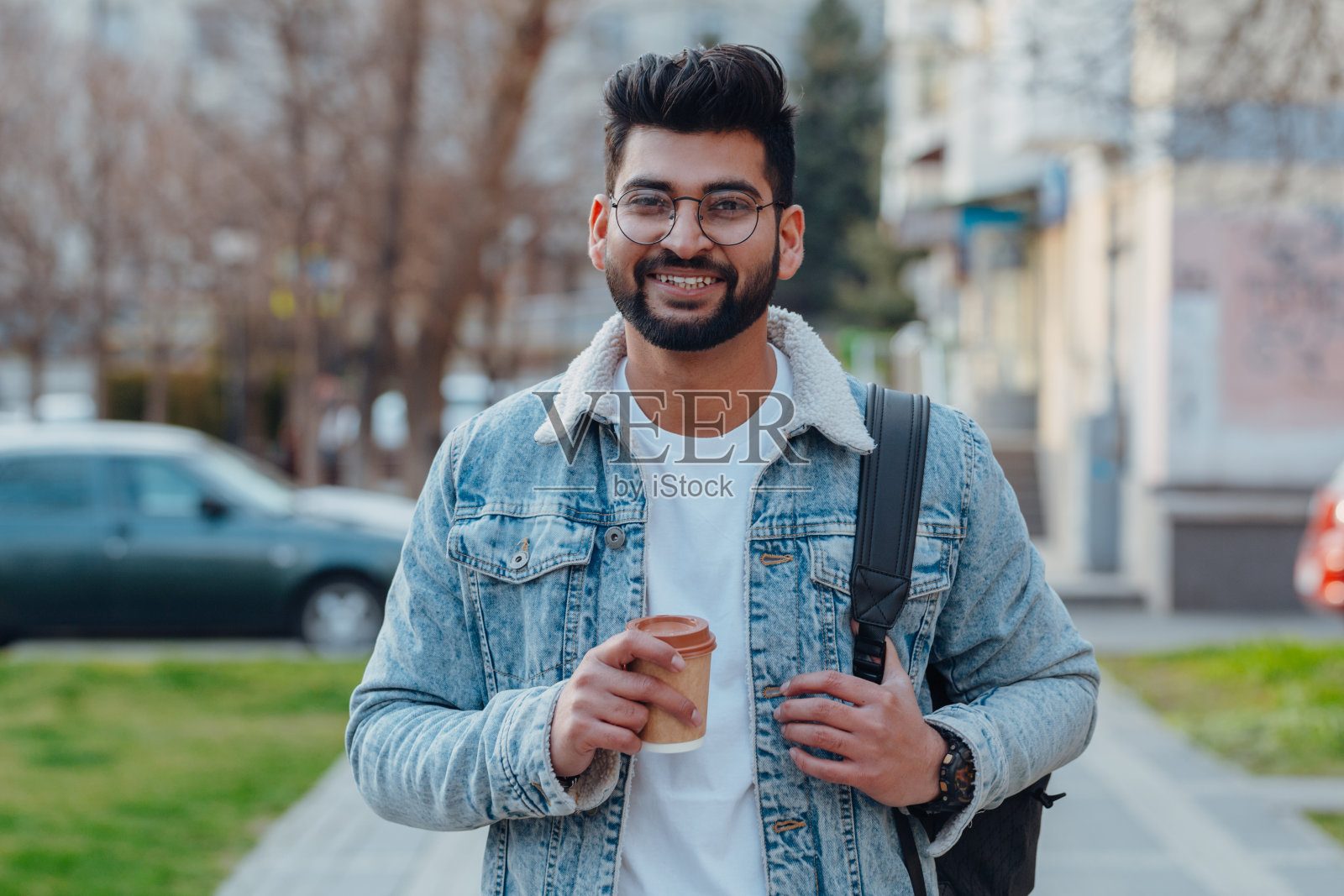 留着胡子的印度男人在街上喝外卖咖啡。照片摄影图片