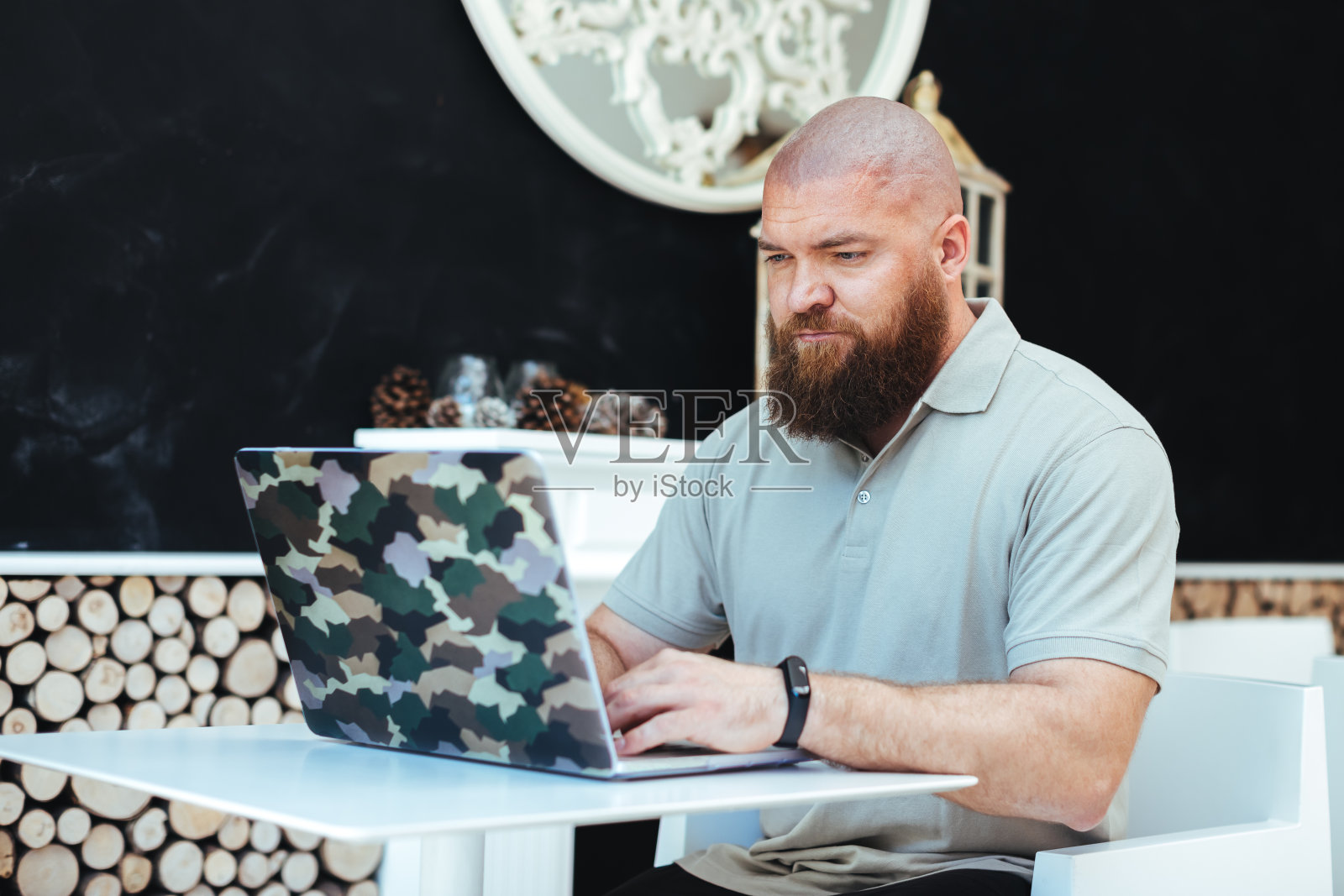 年轻的大胡子嬉皮士使用笔记本电脑，在家里工作，智能工作(远程工作)的概念照片摄影图片