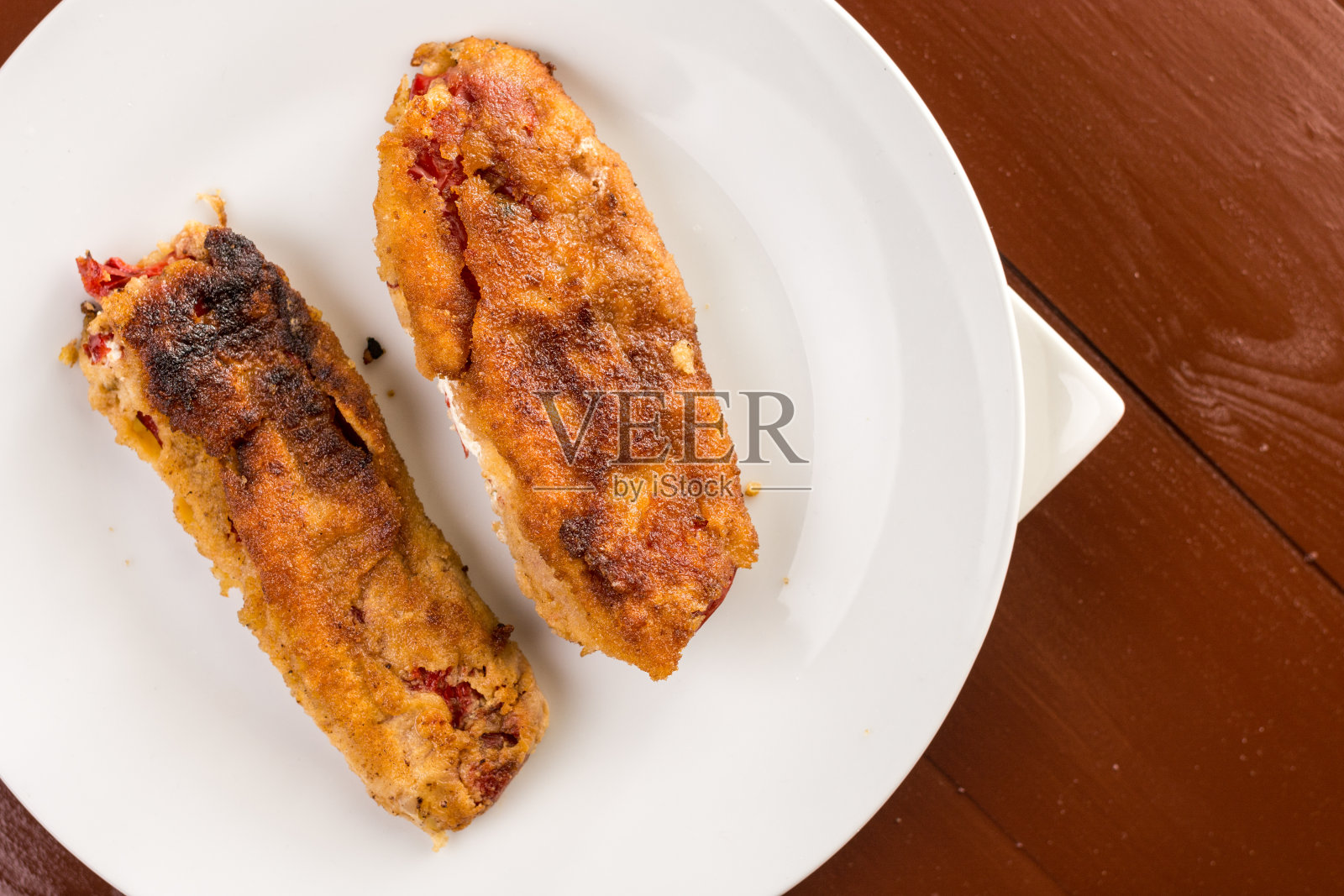 将煎好的红辣椒粉平放在煎好的鸡蛋上，放在棕色的餐桌上照片摄影图片