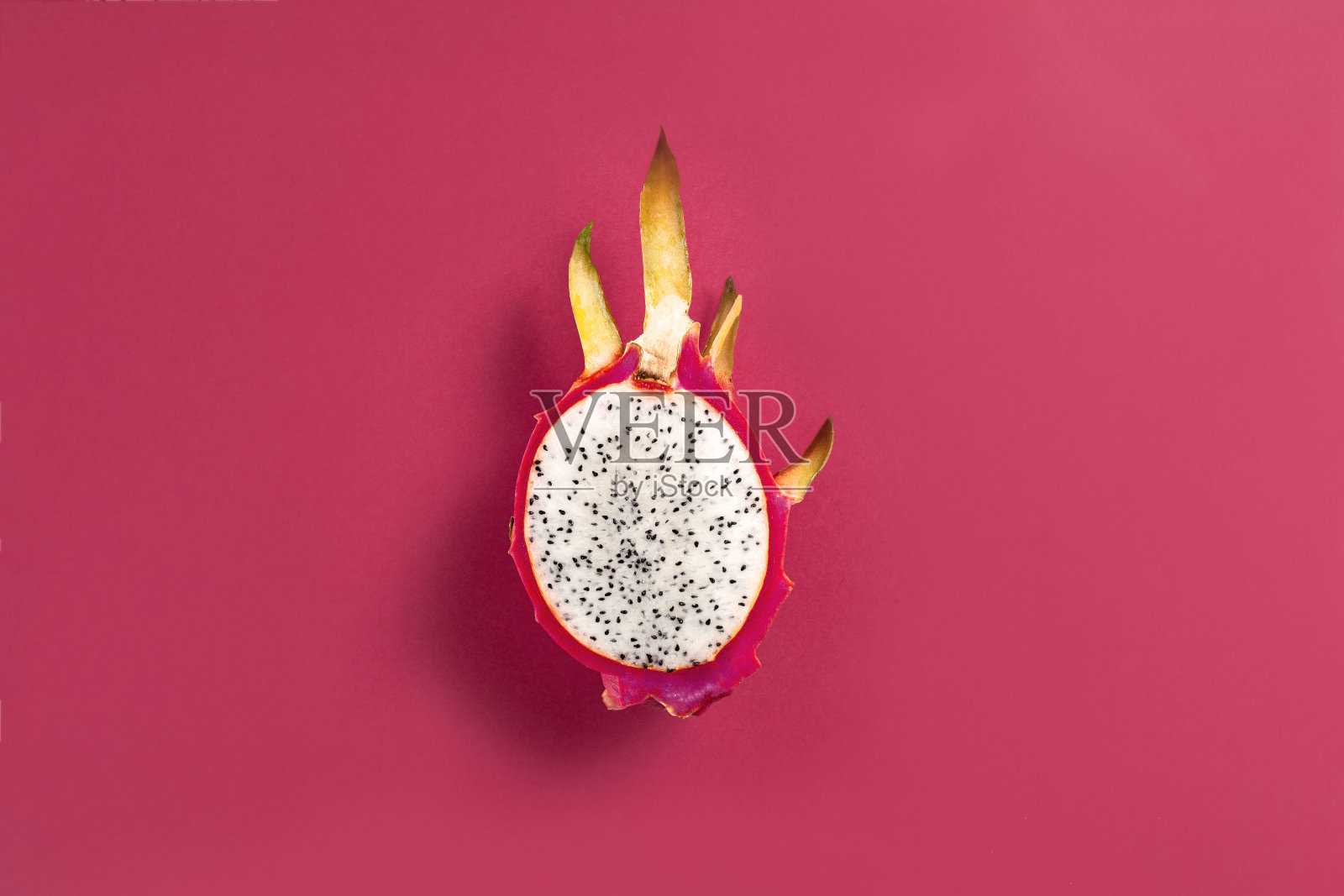 火龙果半在紫红色的底色上照片摄影图片