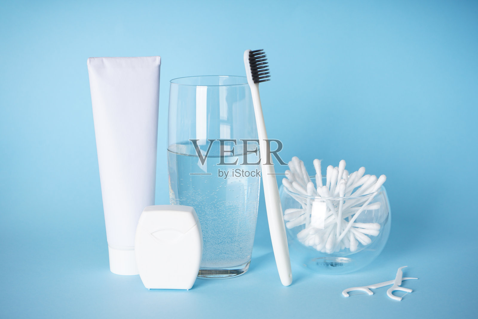 牙科和早晨概念牙刷和一杯水与口腔护理产品在一个蓝色的背景。照片摄影图片