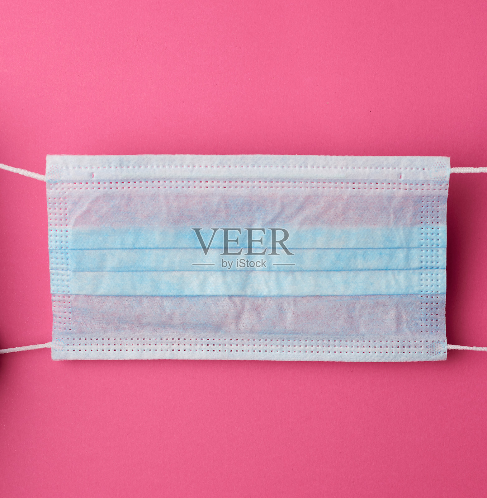 医用无纺布口罩，粉红色背景上有白色橡皮筋照片摄影图片