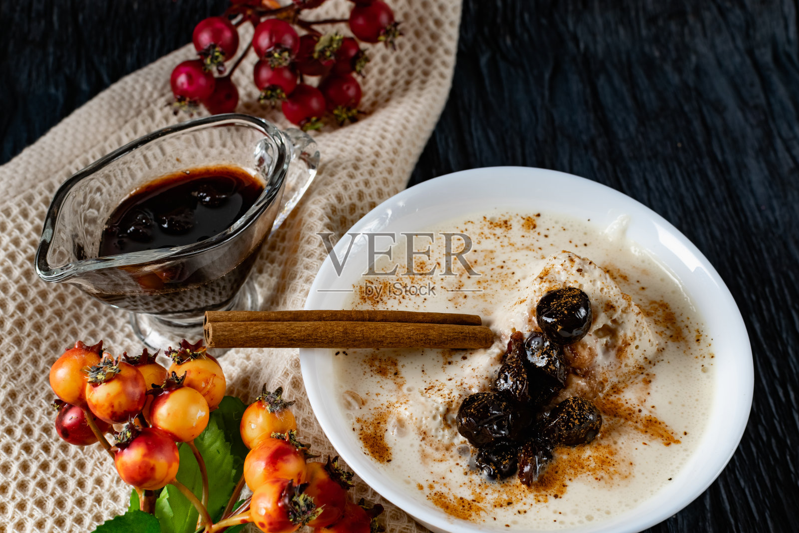 酸奶甜点，与恒温烹饪，用成熟的樱桃浆果在糖浆装饰，在一个深色的背景果酱酱和肉桂棒照片摄影图片