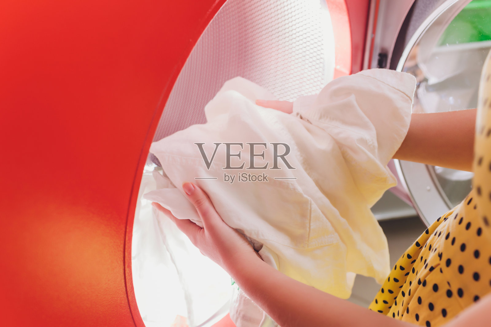 在干洗店将衣物放入洗衣机的手。照片摄影图片