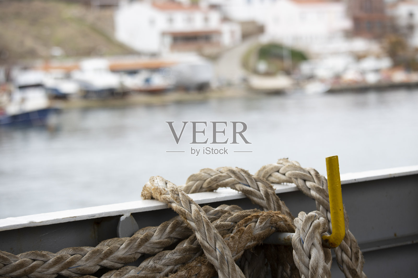 绳子系在船上。背景是海滩上模糊的建筑物和船只。照片摄影图片