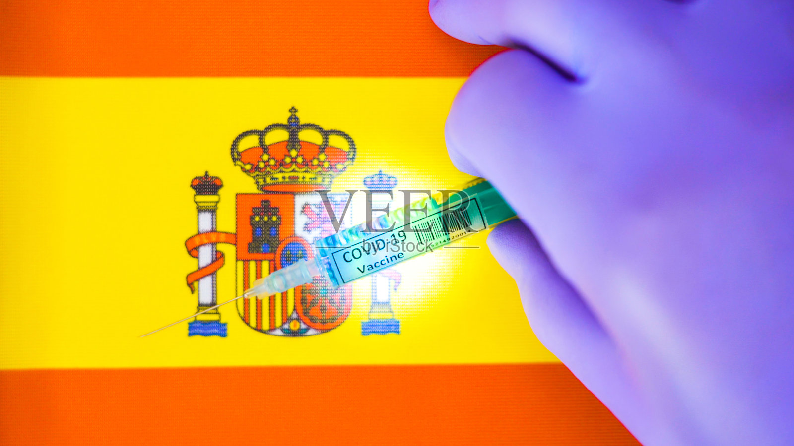 西班牙国旗顶部的疫苗注射器感染了COVID-19冠状病毒照片摄影图片