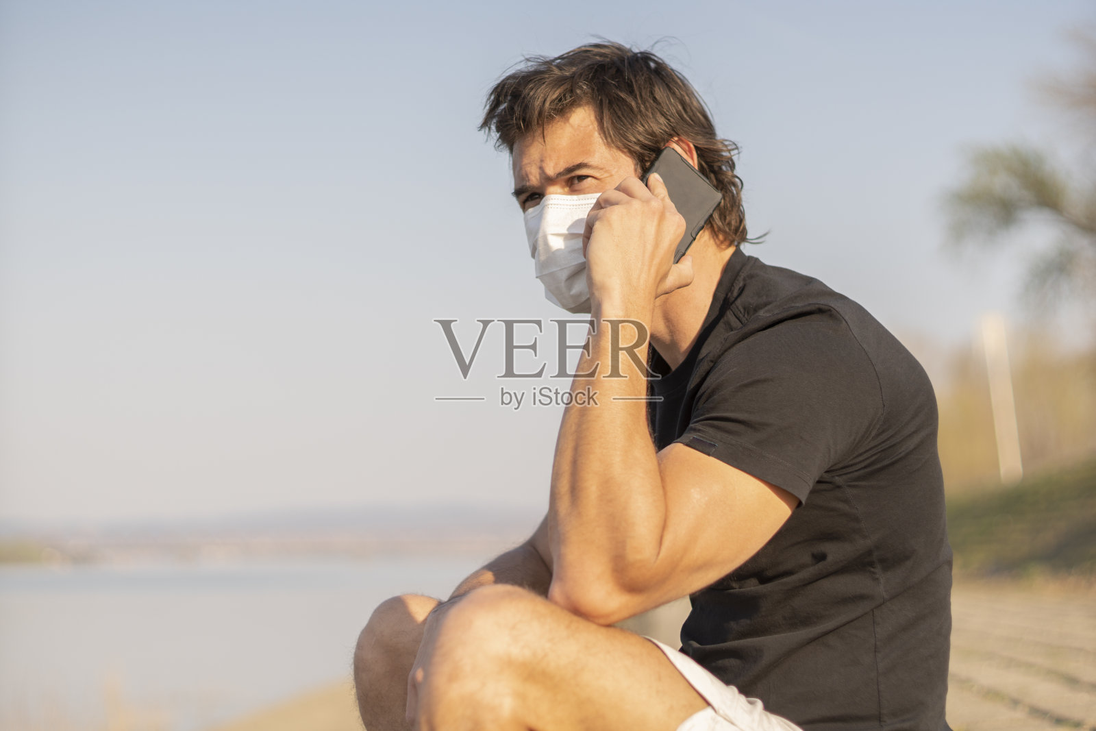 男子戴口罩，以预防病毒和保护，同时使用手机照片摄影图片