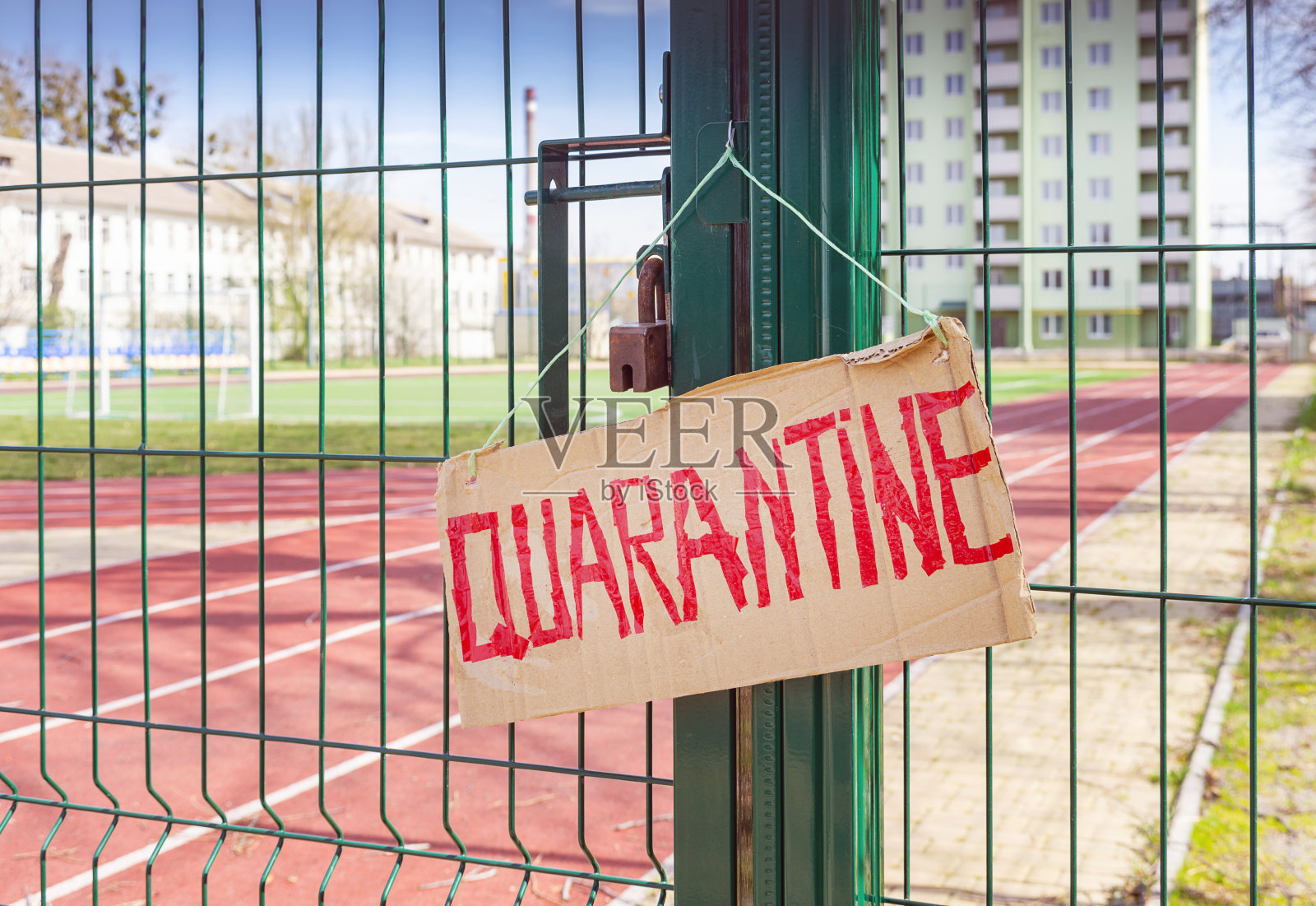 封闭运动场的围栏，上面有手工制作的纸板警告标志，上面用红色胶带写着“检疫隔离”。冠状病毒大流行、covid-19、概念。照片摄影图片